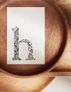 Visitenkarte mit stilisierter Hoizpeda Bildmarke "h", geprägt auf hochwertigem Papier, platziert auf einer natürlichen Holzoberfläche.